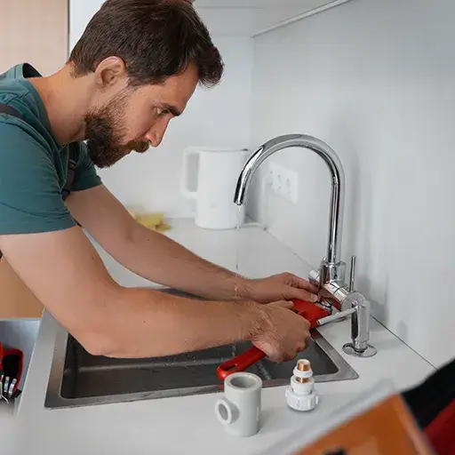 Handyman repairing kitchen faucet and fixing minor plumbing leak